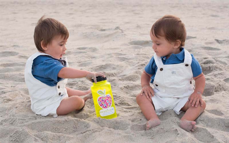 Twins at the beach playing with a Little Red Wagon drink bottle